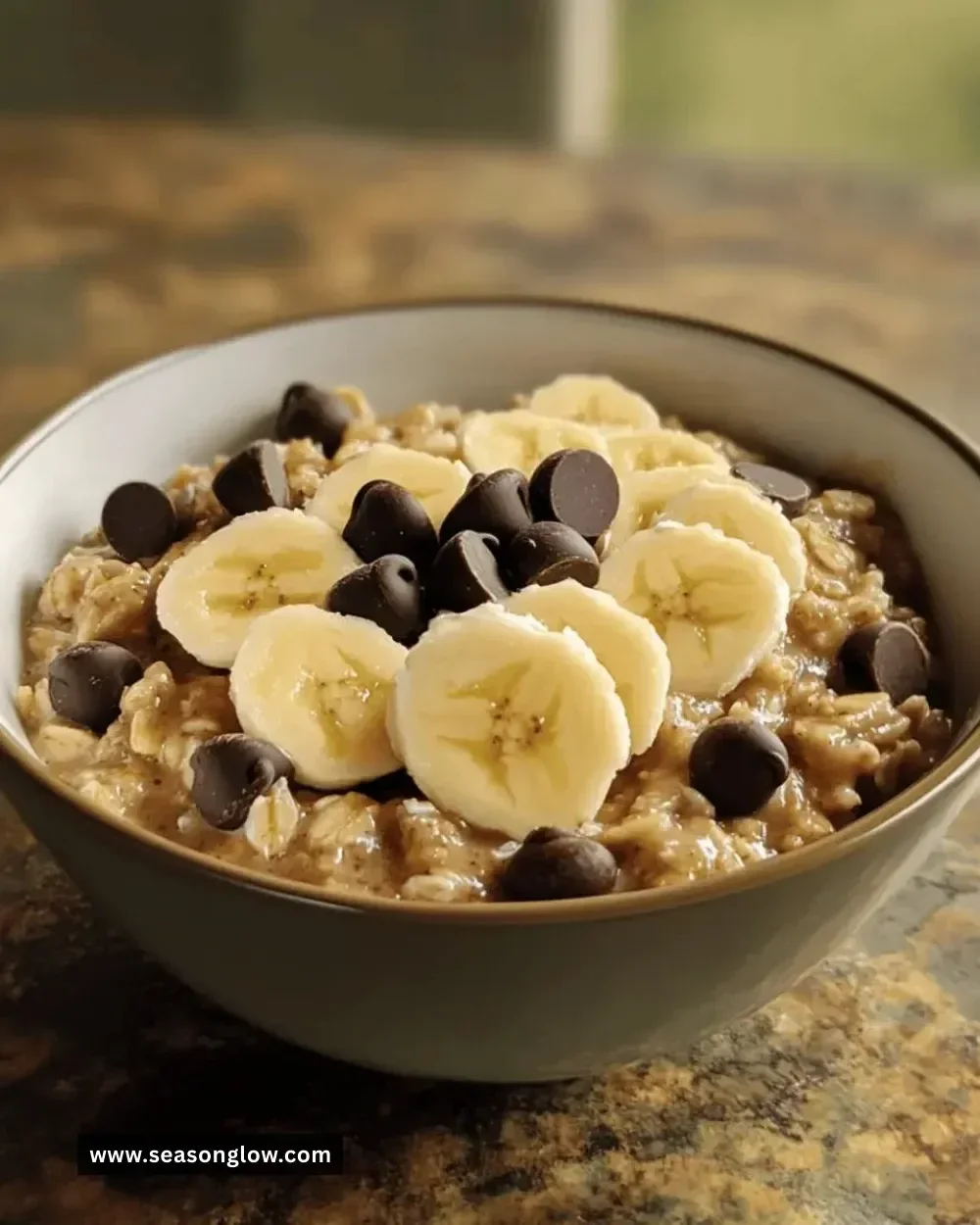 Bowl of banana chocolate chip oatmeal topped with fresh banana slices