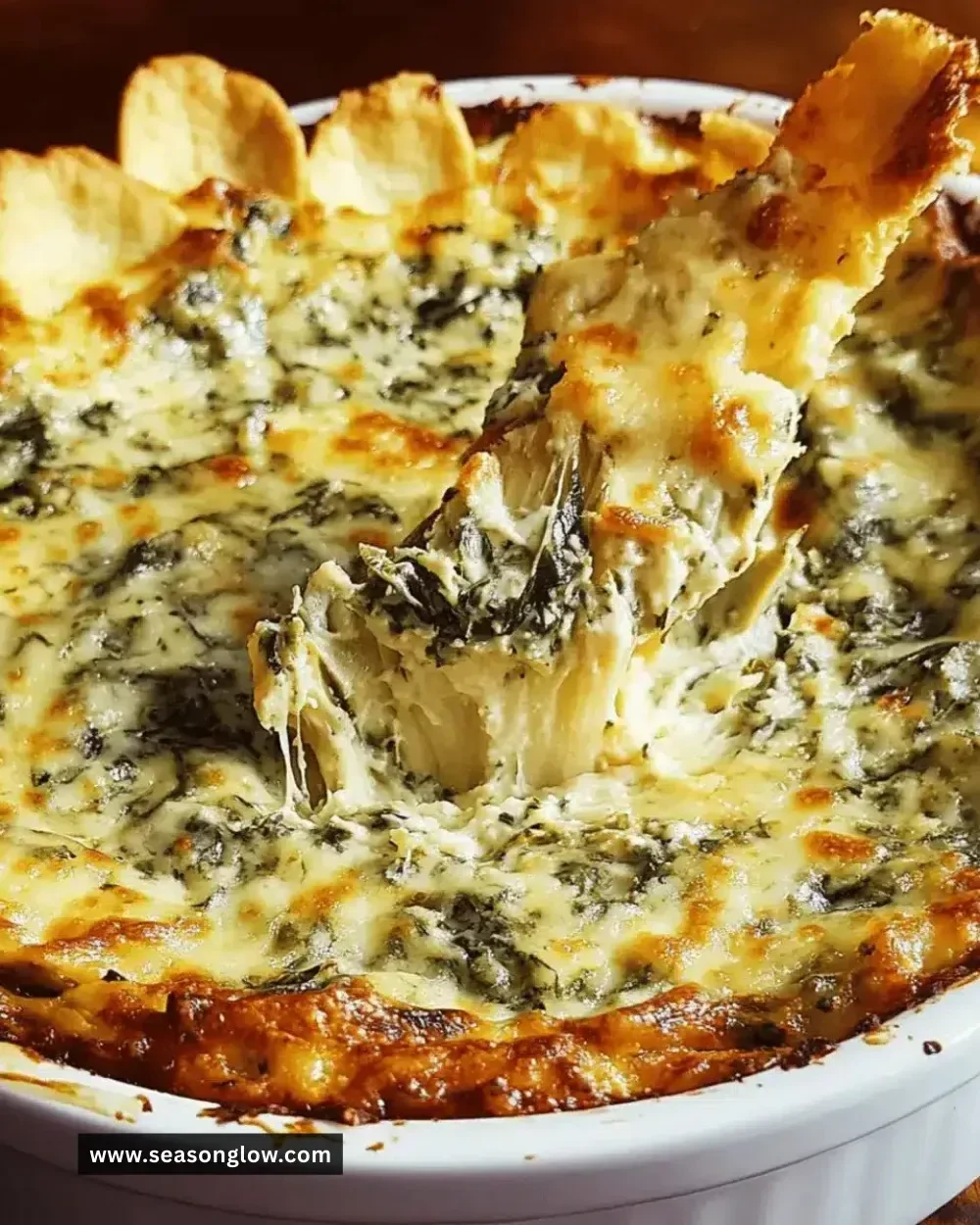 Cheesy spinach artichoke dip served in a bowl with tortilla chips