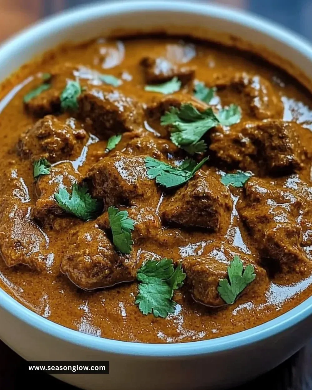 Coconut Braised Beef Curry served in a bowl with spices and herbs