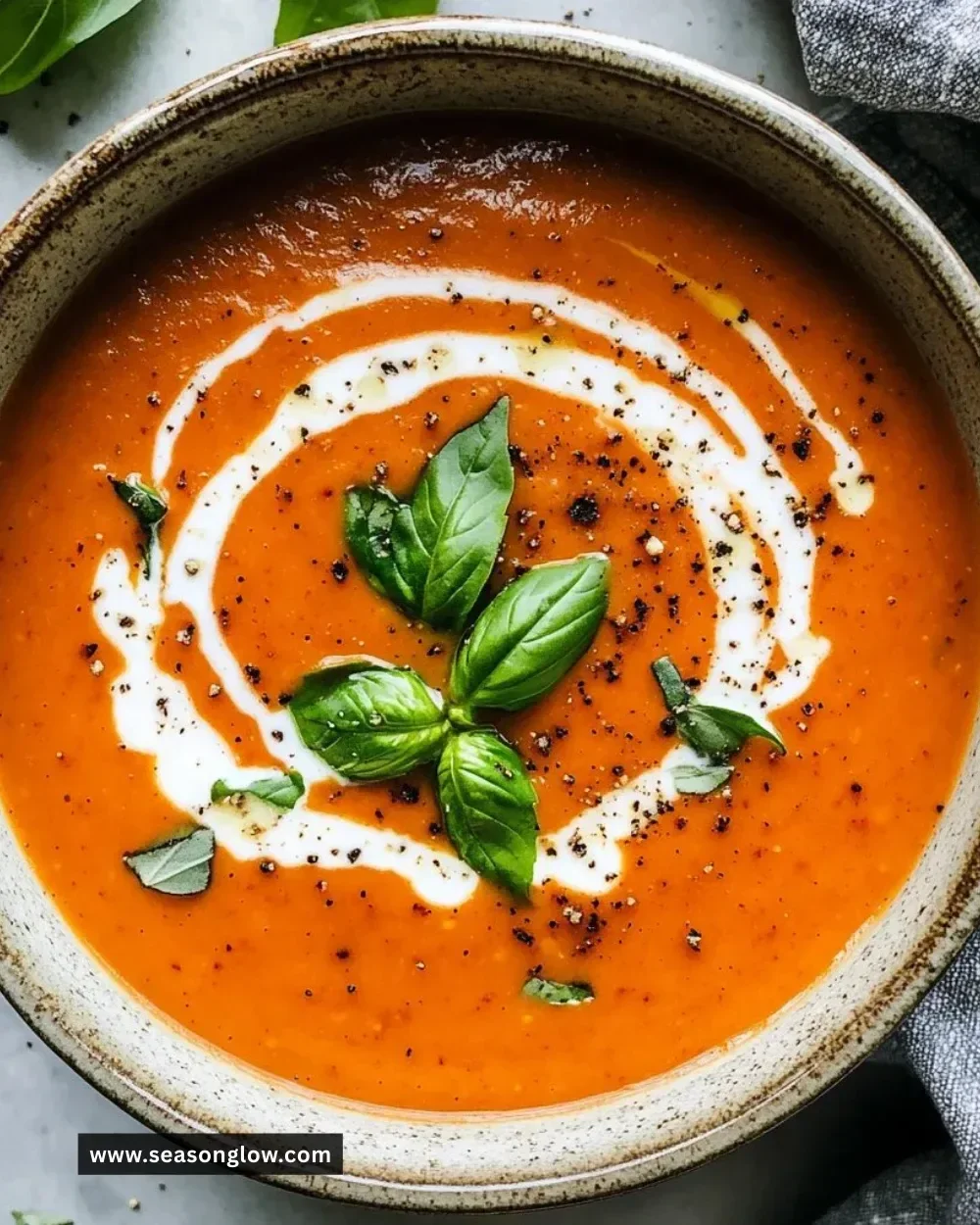 Delicious creamy tomato basil soup in a bowl garnished with fresh basil leaves.