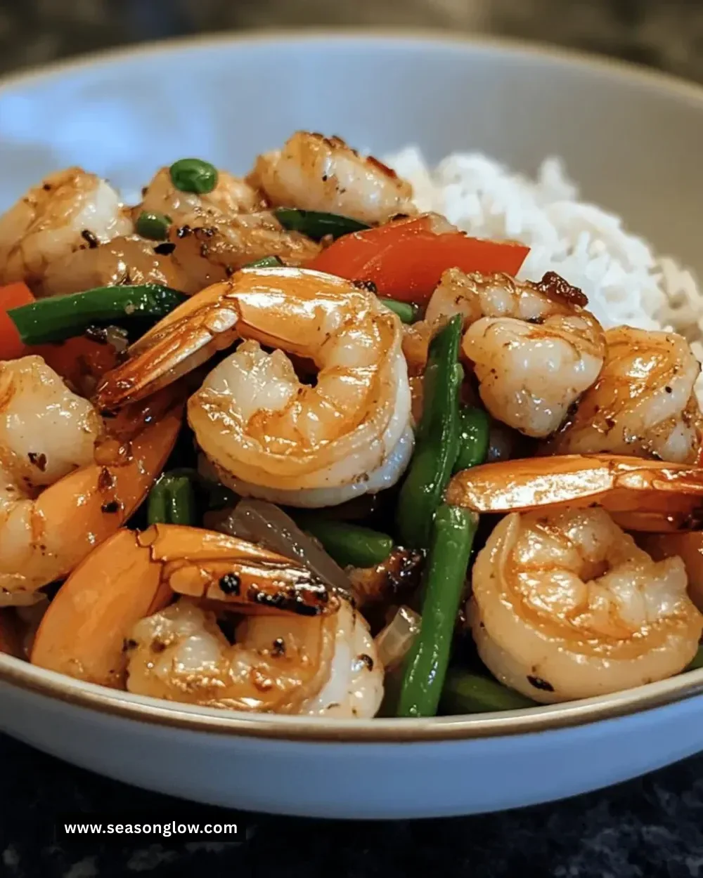 A vibrant shrimp stir-fry with colorful vegetables and rice on a plate.