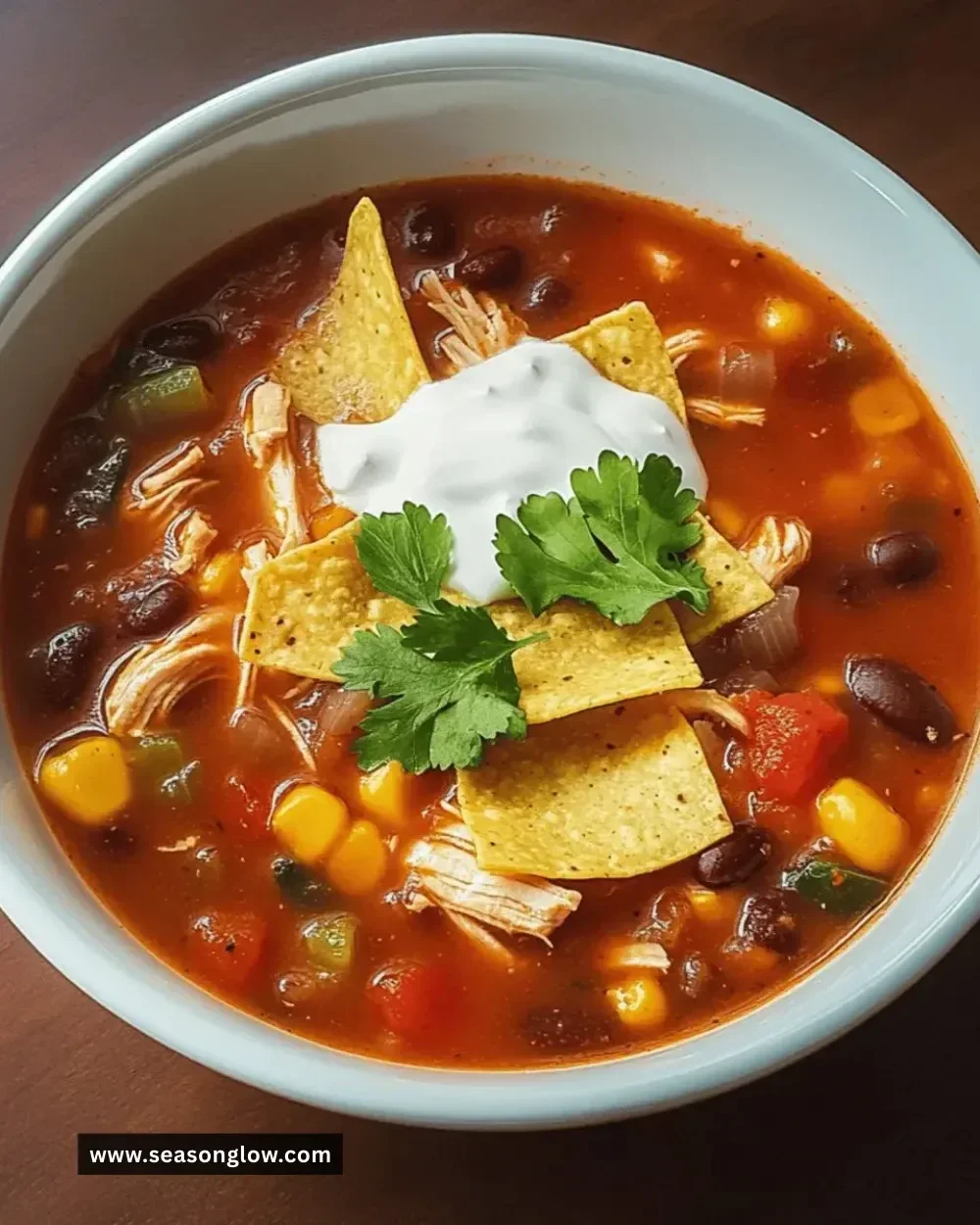 Bowl of easy crockpot chicken tortilla soup topped with avocado and tortilla strips.