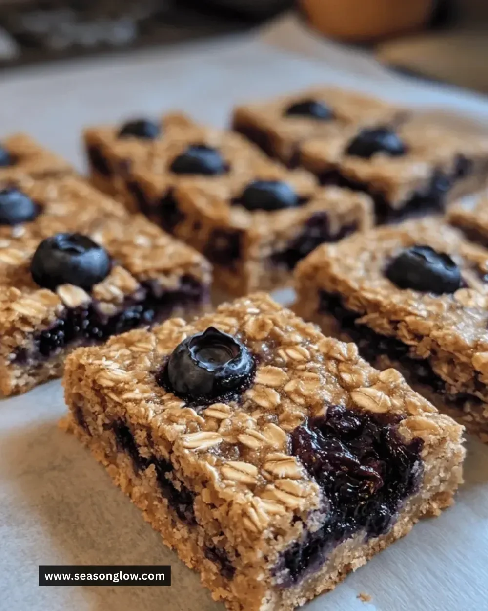 Baked oatmeal blueberry bars served on a wooden plate with fresh blueberries