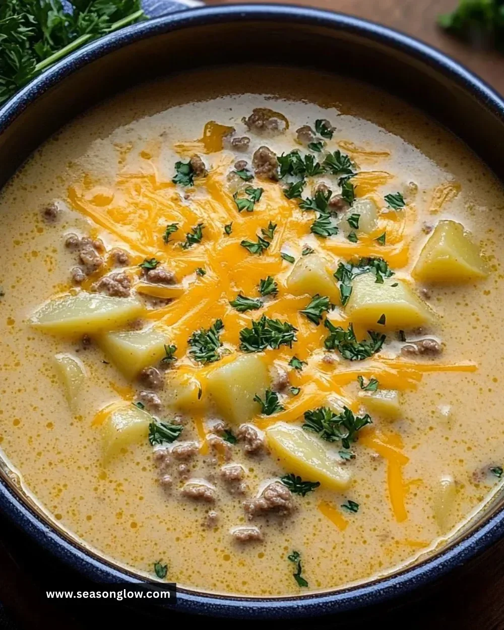 Bowl of cheesy beef and potato soup garnished with herbs