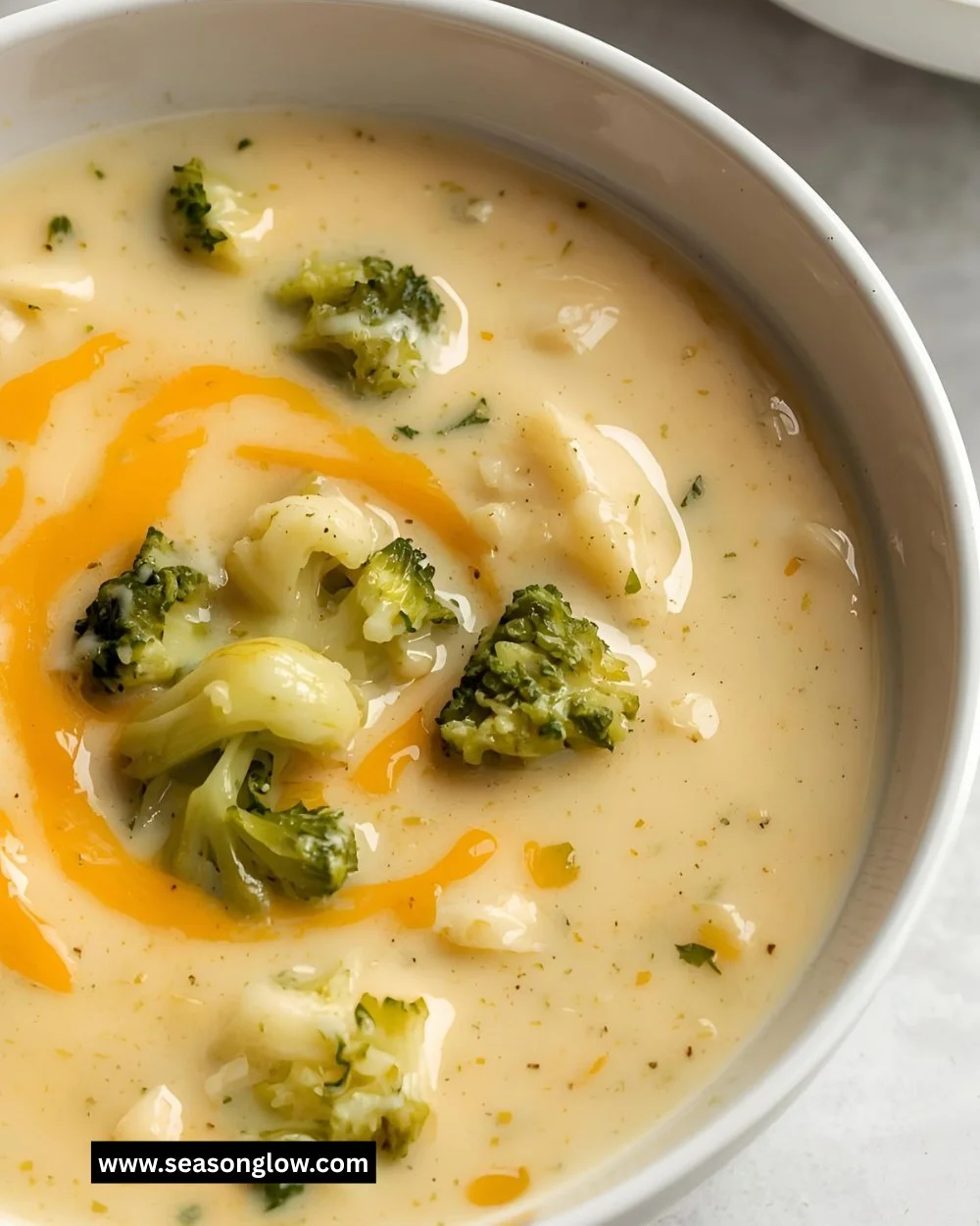 Bowl of creamy broccoli cheddar soup garnished with fresh herbs.
