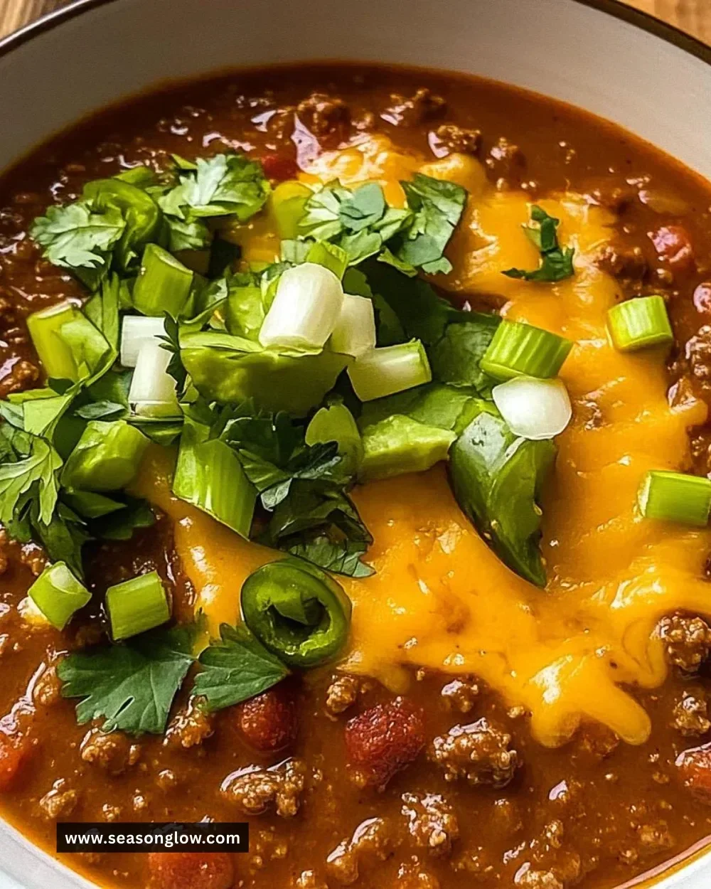 Crockpot Spicy Queso Beef Chili in a bowl, topped with cheese and cilantro.