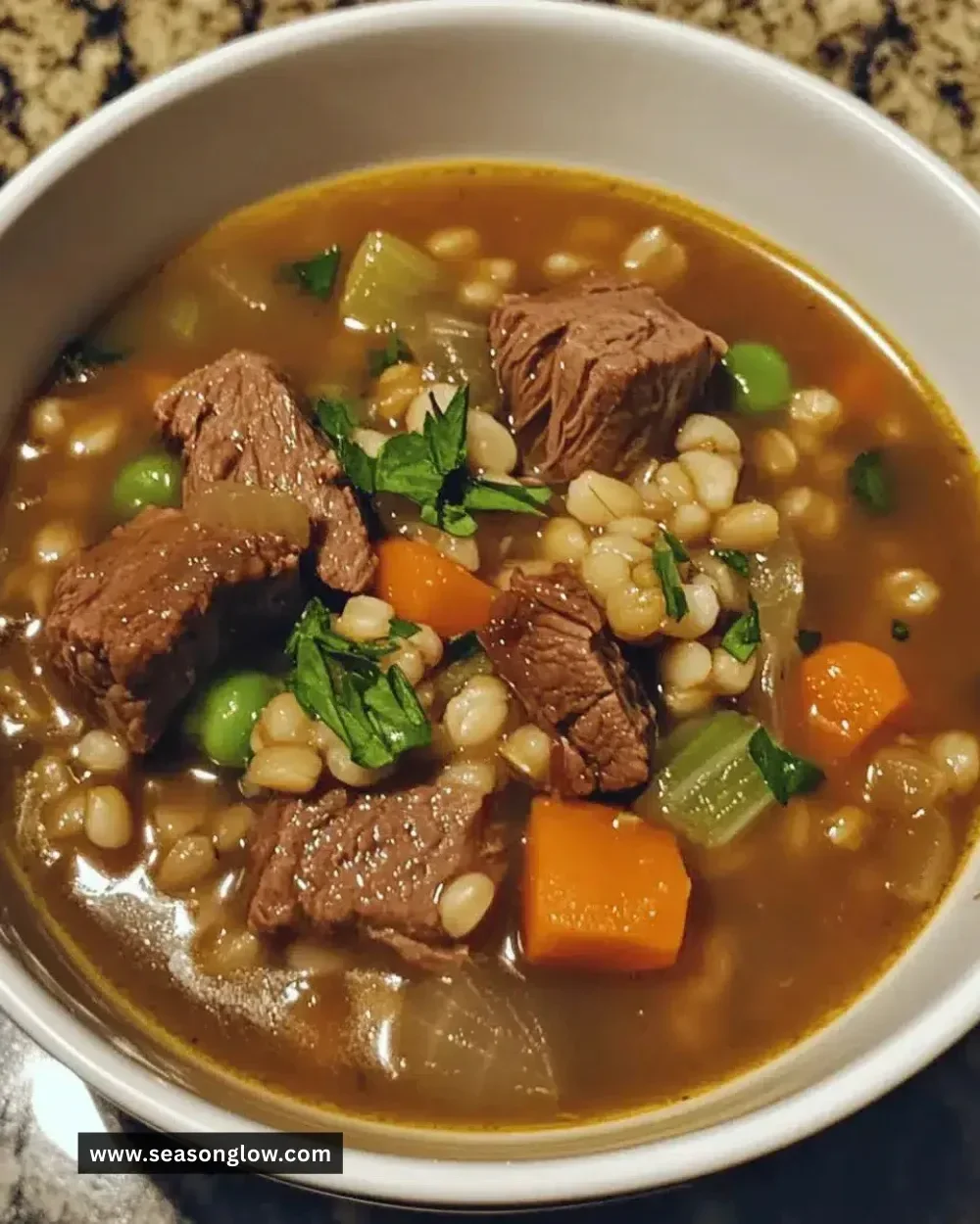 Bowl of easy cozy beef barley soup with vegetables and herbs