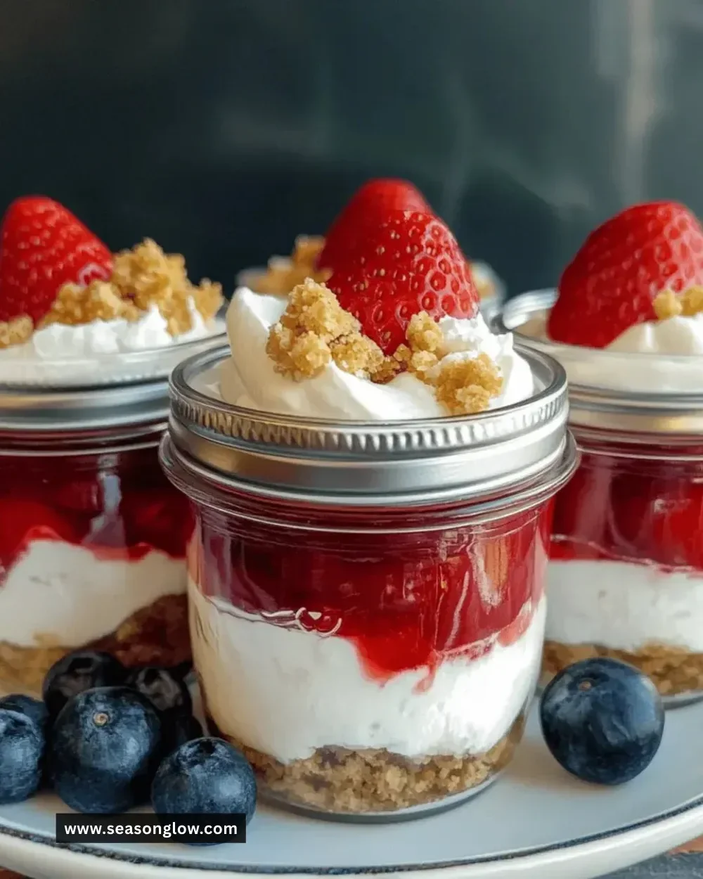 Delicious strawberry cheesecake parfait jars layered with strawberries and cheesecake.