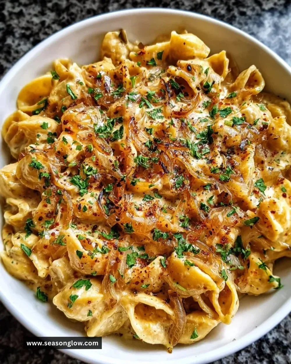 Creamy French onion pasta garnished with herbs and cheese in a bowl