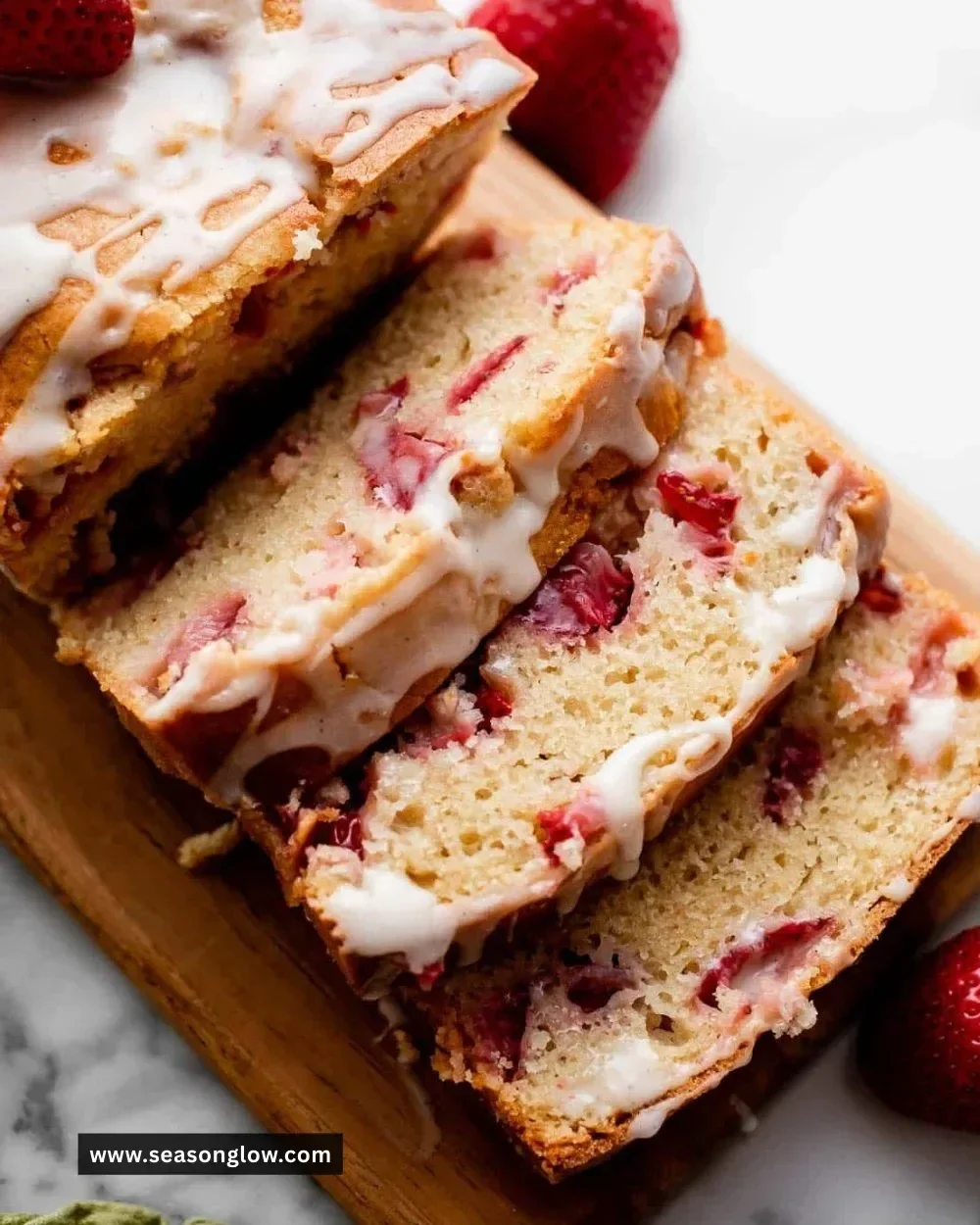Loaf of glazed strawberry bread with fresh strawberries on top
