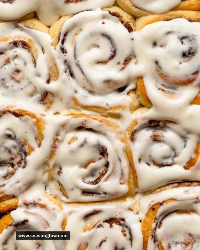 Delicious homemade overnight cinnamon rolls topped with creamy icing on a wooden table.