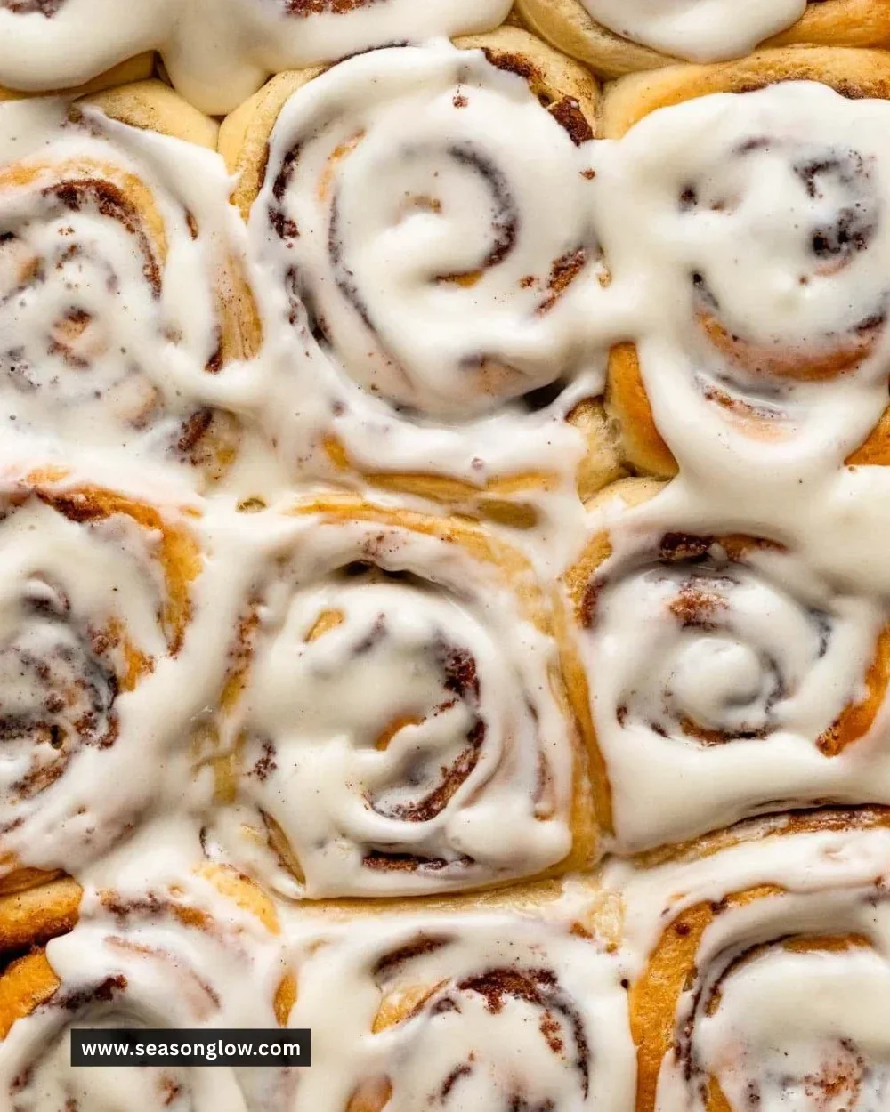 Delicious homemade overnight cinnamon rolls topped with creamy icing on a wooden table.
