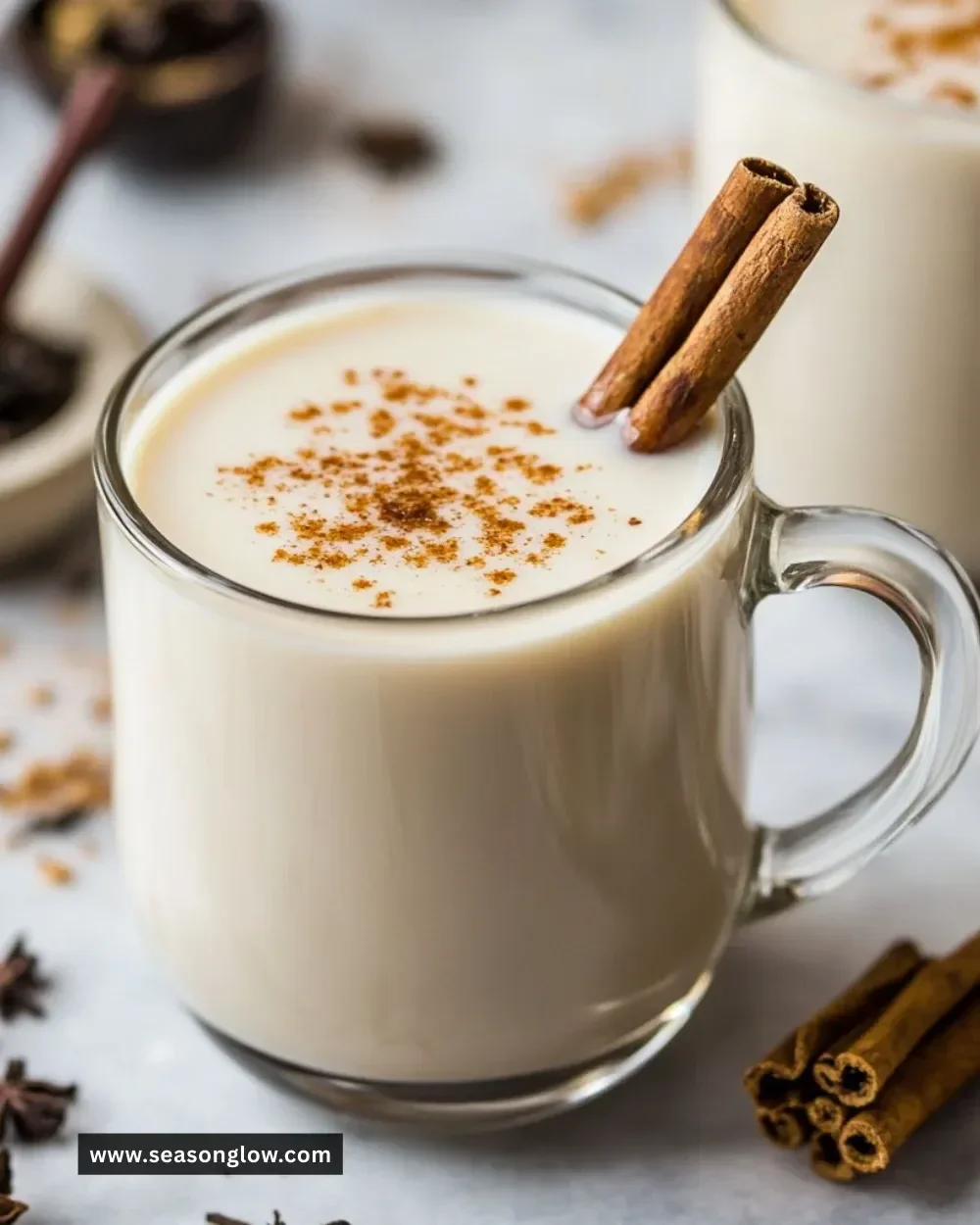 A cup of homemade vanilla cinnamon milk tea garnished with cinnamon sticks.