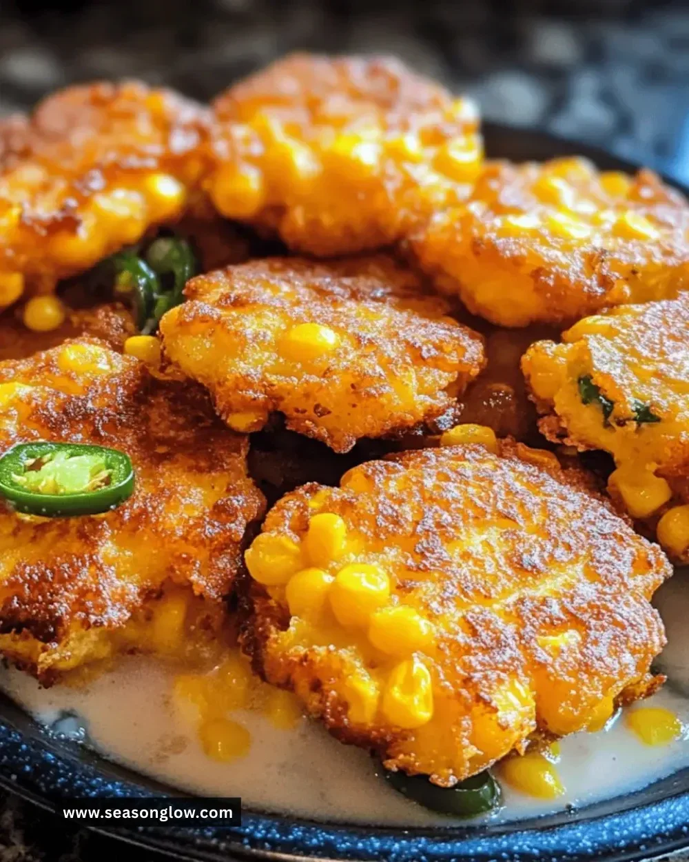 Plate of cheesy jalapeño corn fritters garnished with fresh herbs
