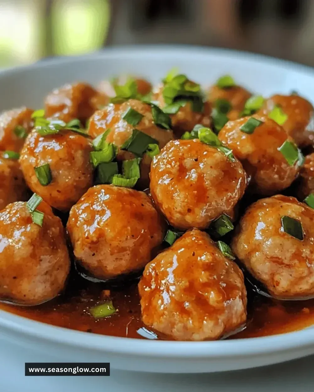 Plate of juicy sweet chili chicken meatballs garnished with green onions.