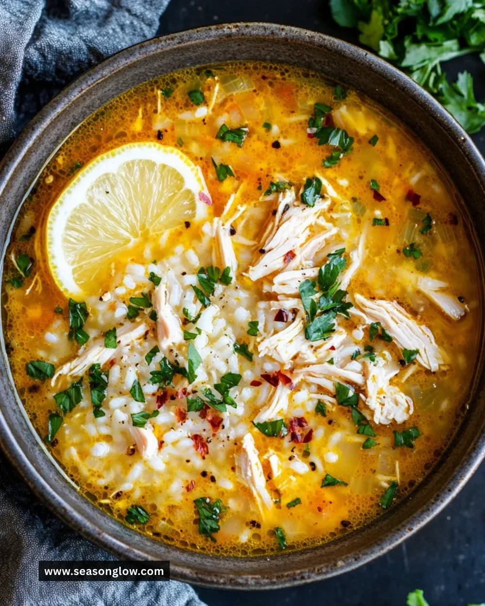 A bowl of Lemon Ginger Turmeric Chicken and Rice Soup with fresh ingredients.