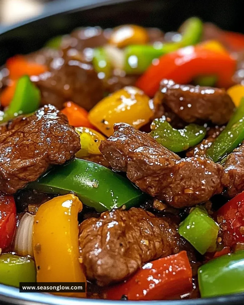Delicious pepper steak cooked in a crock pot, served with colorful vegetables.