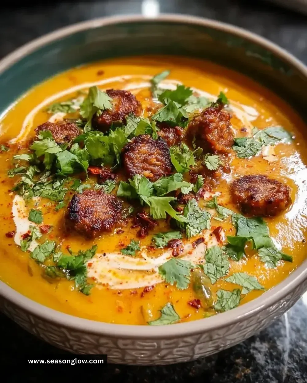 Spicy chorizo pumpkin soup served in a bowl with fresh herbs
