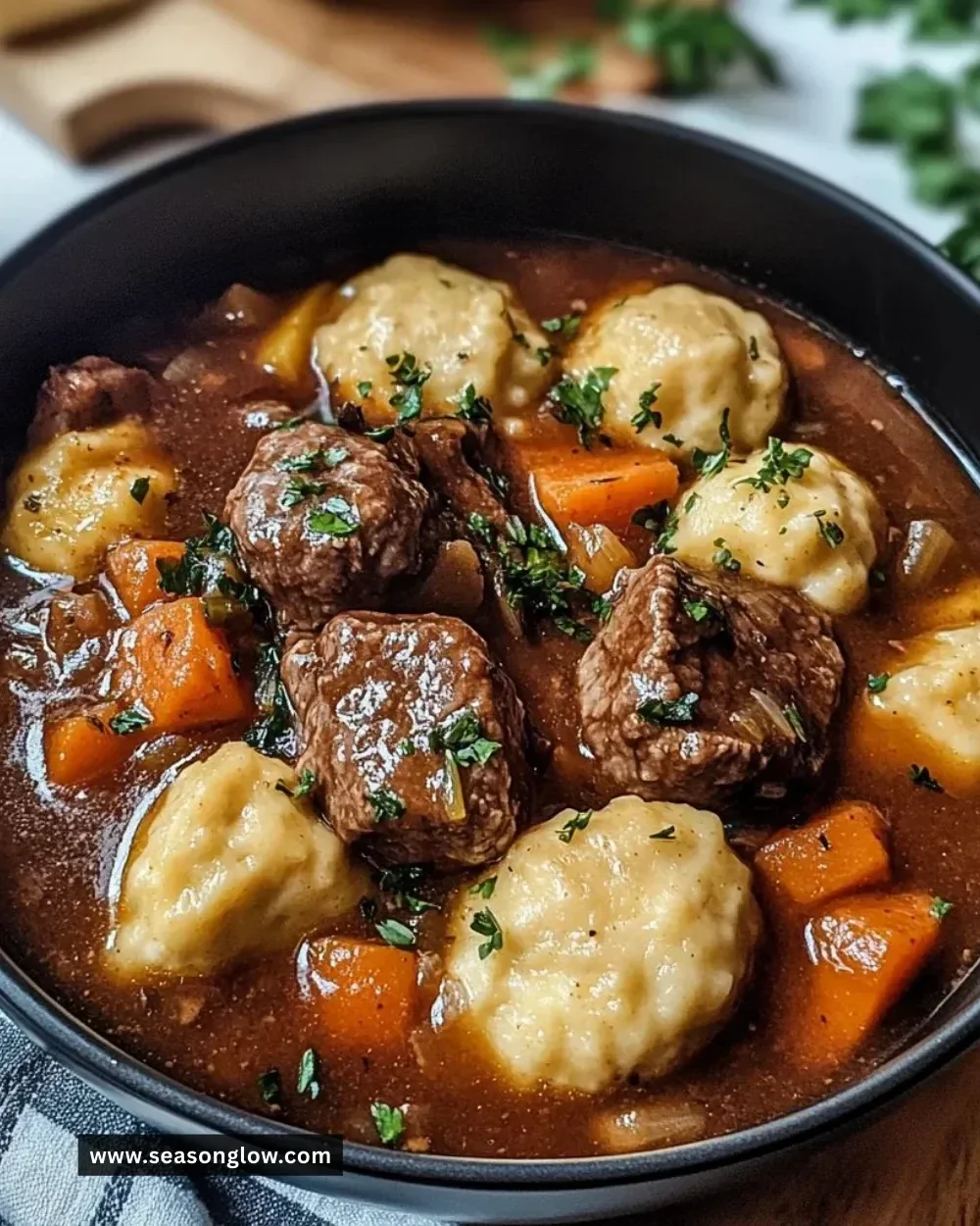 Bowl of tasty beef stew with dumplings, garnished with herbs