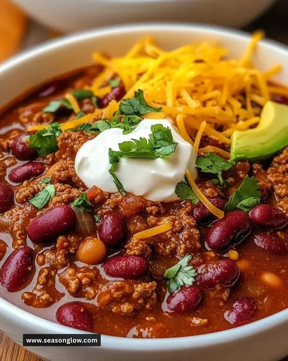 Bowl of Texas Roadhouse Chili with ingredients in the background