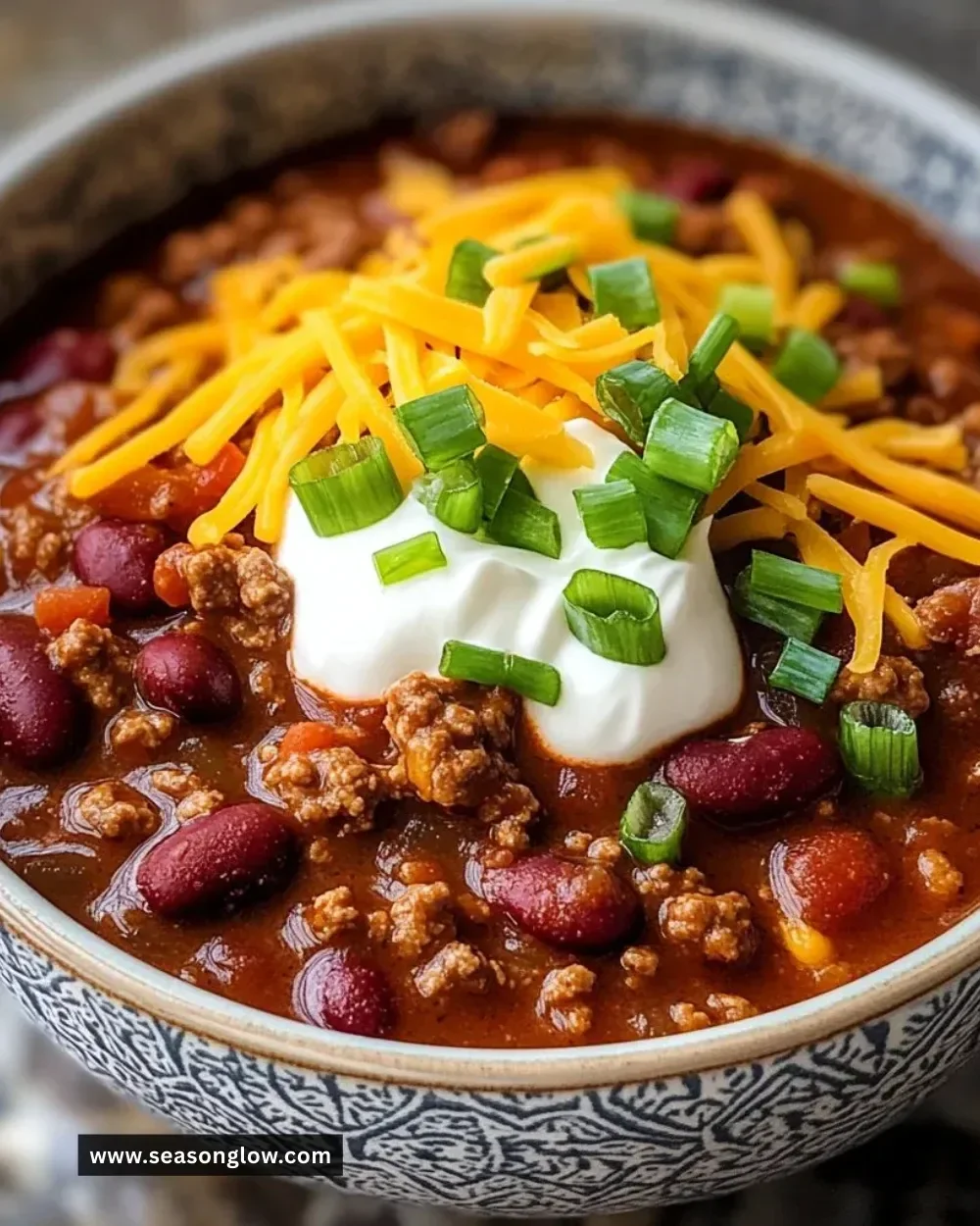 A bowl of the best chili recipe topped with fresh herbs and cheese