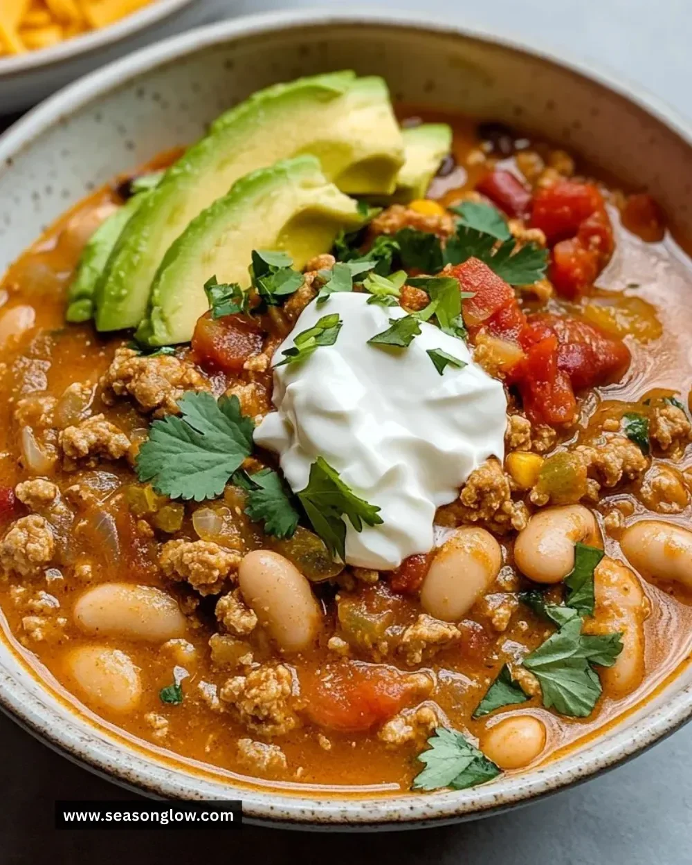 A bowl of Turkey White Bean Chili topped with fresh herbs and spices.