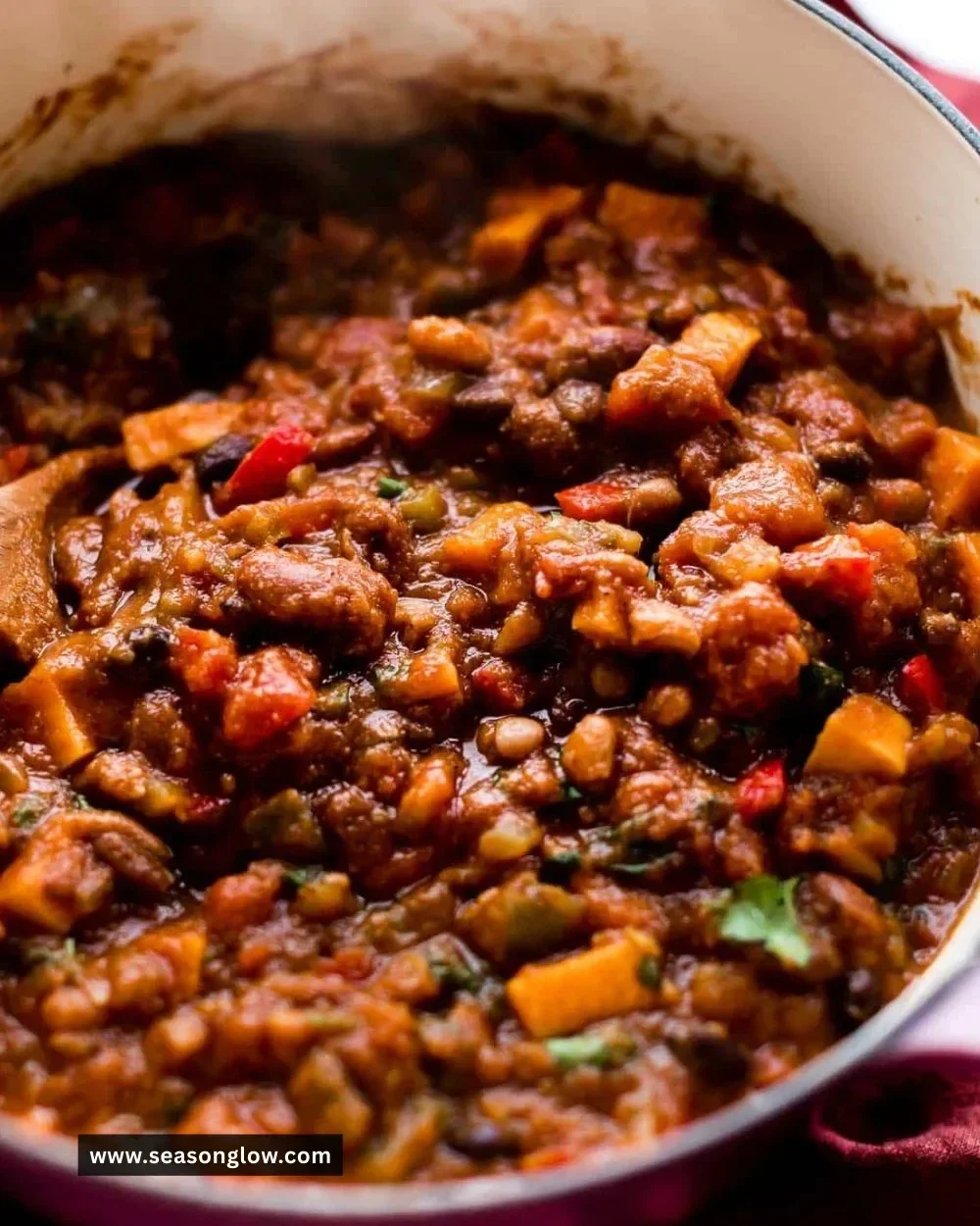 A bowl of Vegetarian Pumpkin Chili topped with herbs and served with bread.