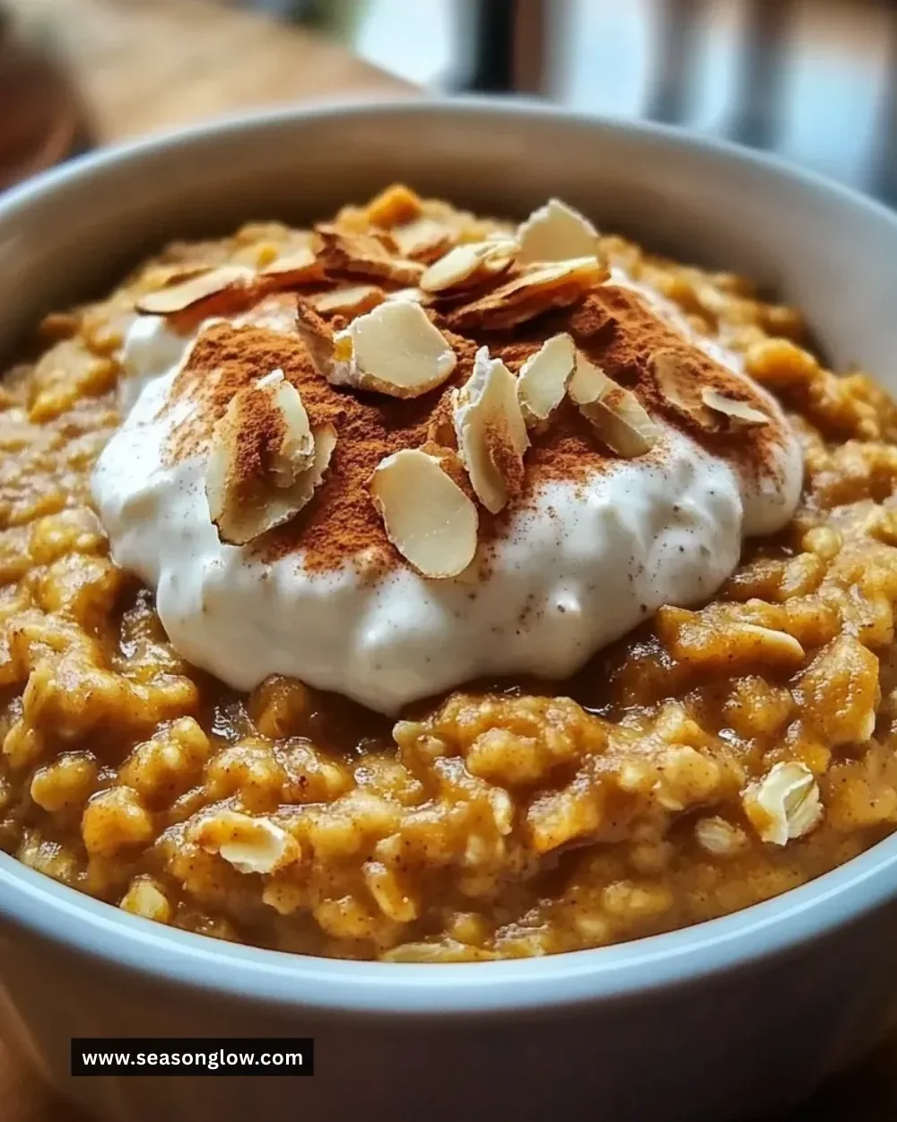 Bowl of warm spiced pumpkin oatmeal topped with nuts and spices