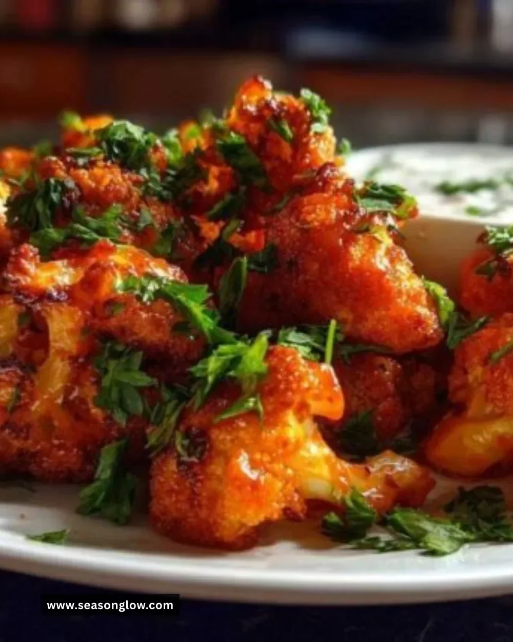 Crispy buffalo cauliflower bites garnished with green onions on a plate