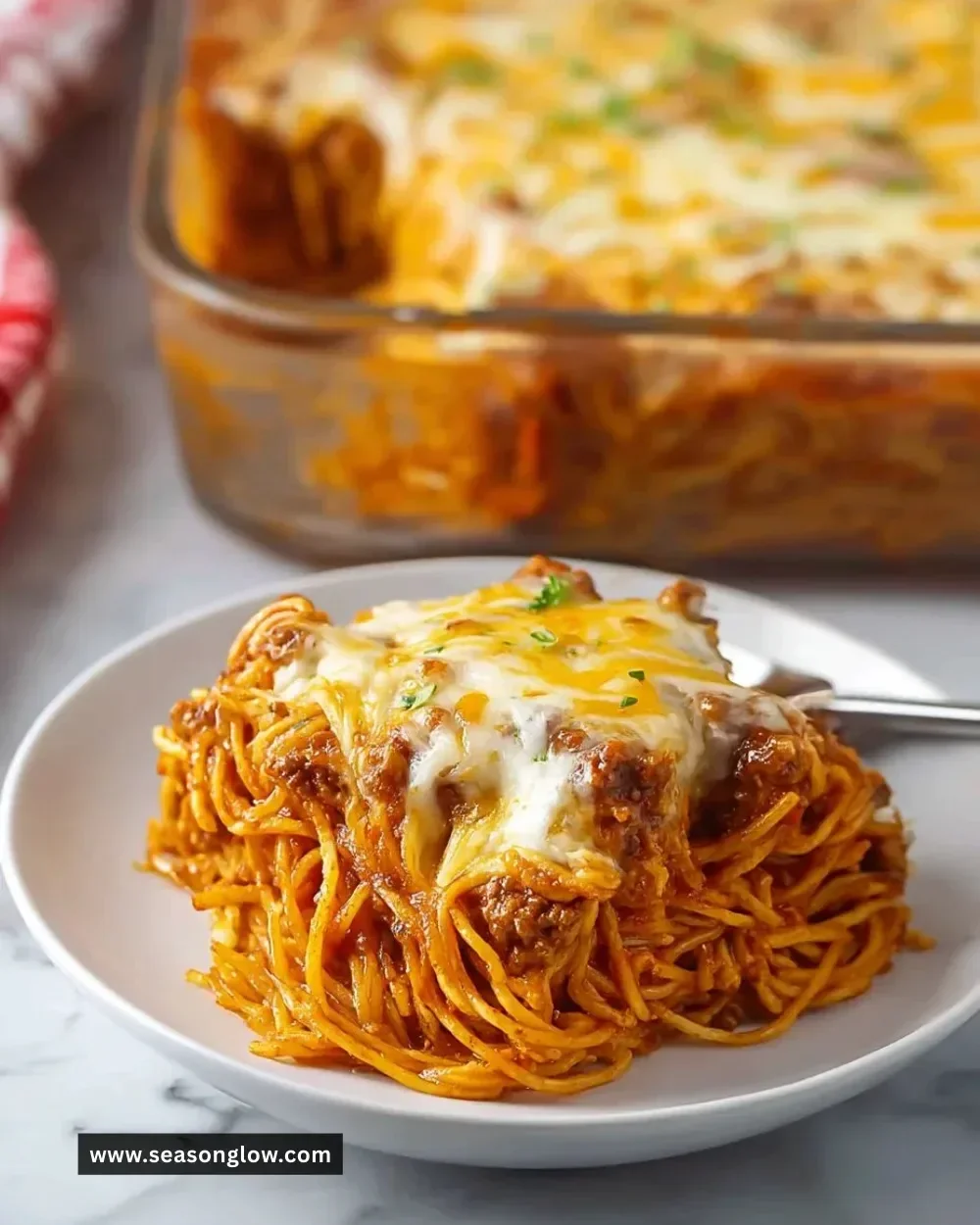 Baked Cream Cheese Spaghetti Casserole topped with cheese and herbs