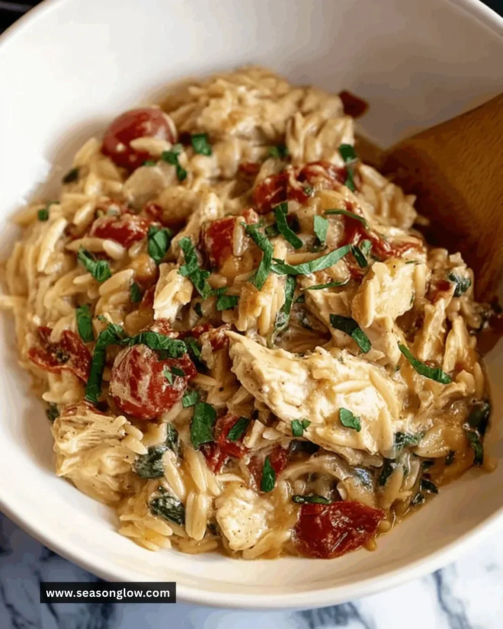 Bowl of Classic Crockpot Tuscan Chicken Orzo with vegetables and herbs