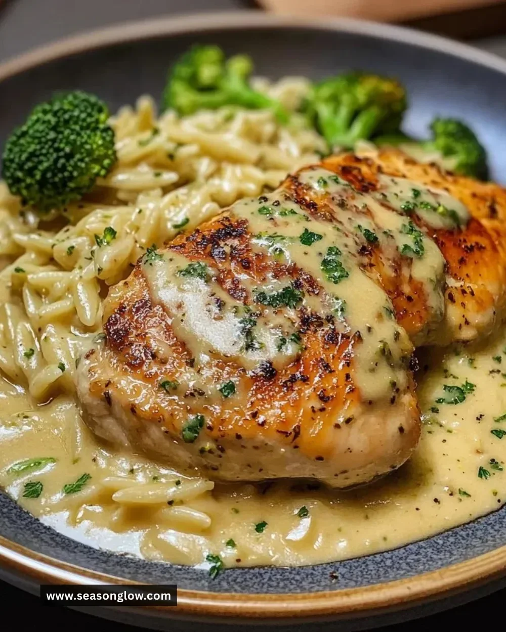 Creamy chicken broccoli orzo dish served in a bowl with a garnish of herbs