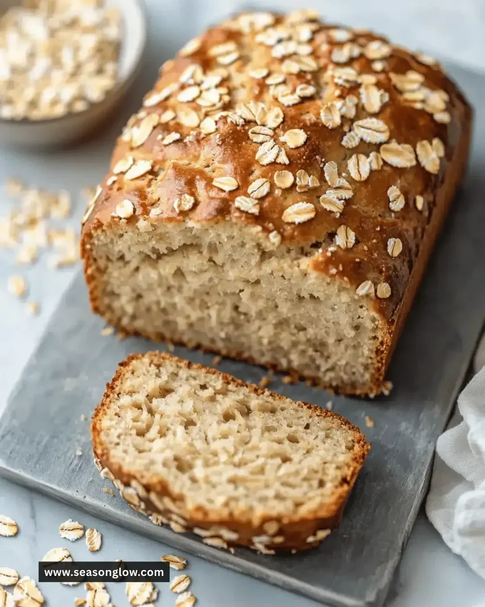 Loaf of Greek yogurt oat bread with a slice cut showing soft texture.