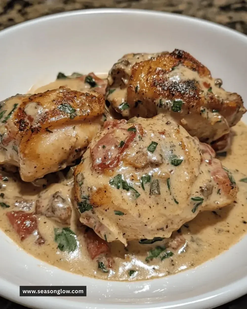 Crockpot creamy Tuscan chicken thighs garnished with herbs and served on a plate