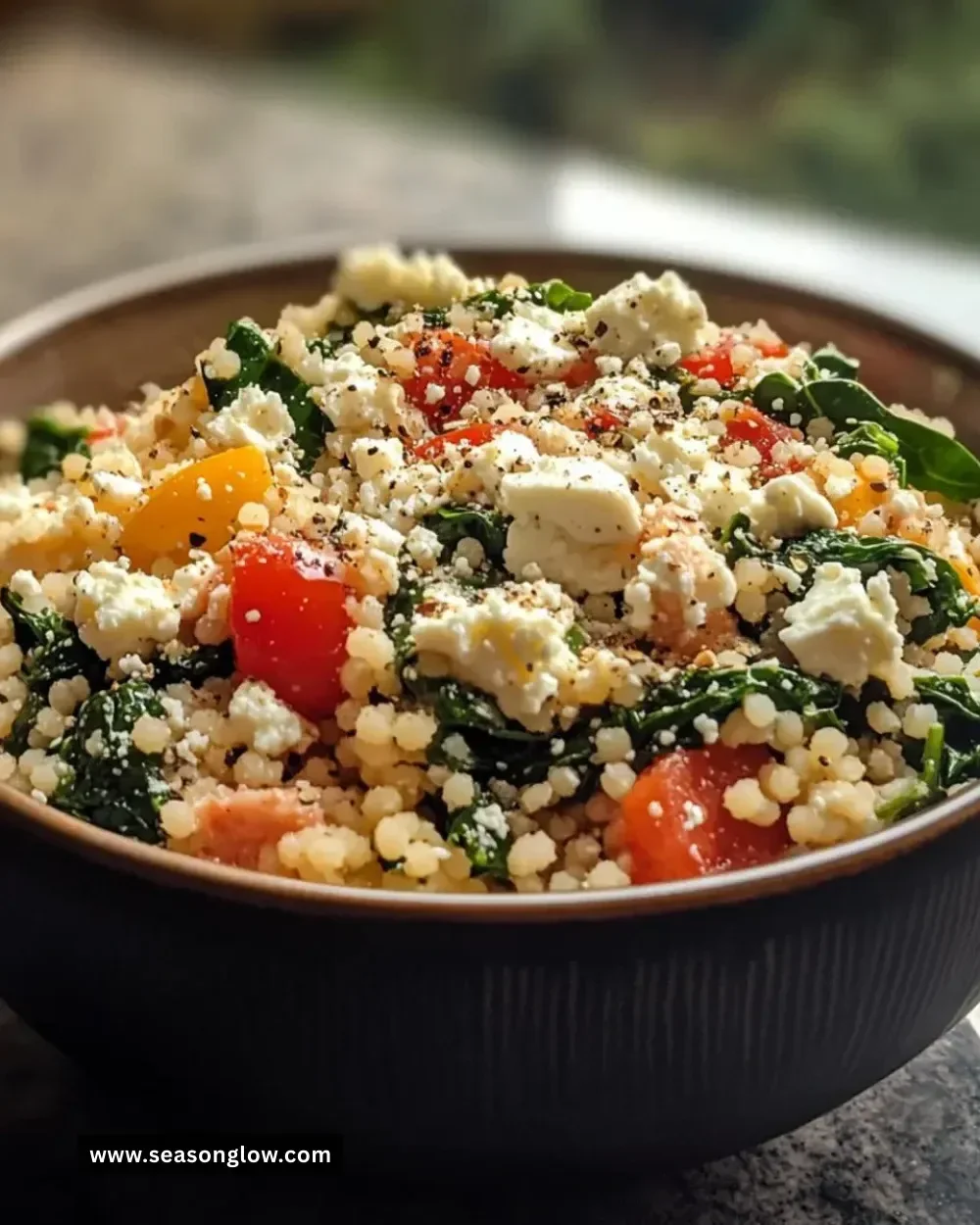 Delicious spinach and feta couscous bowl topped with fresh vegetables