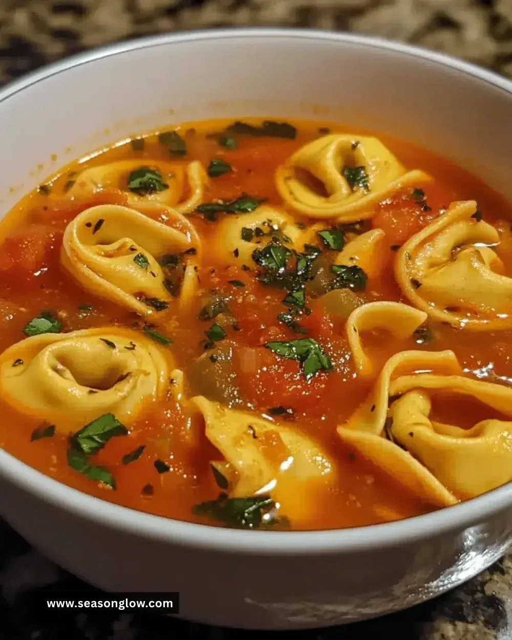 Delicious Easy Tomato Basil Tortellini Soup in a bowl with fresh basil garnish