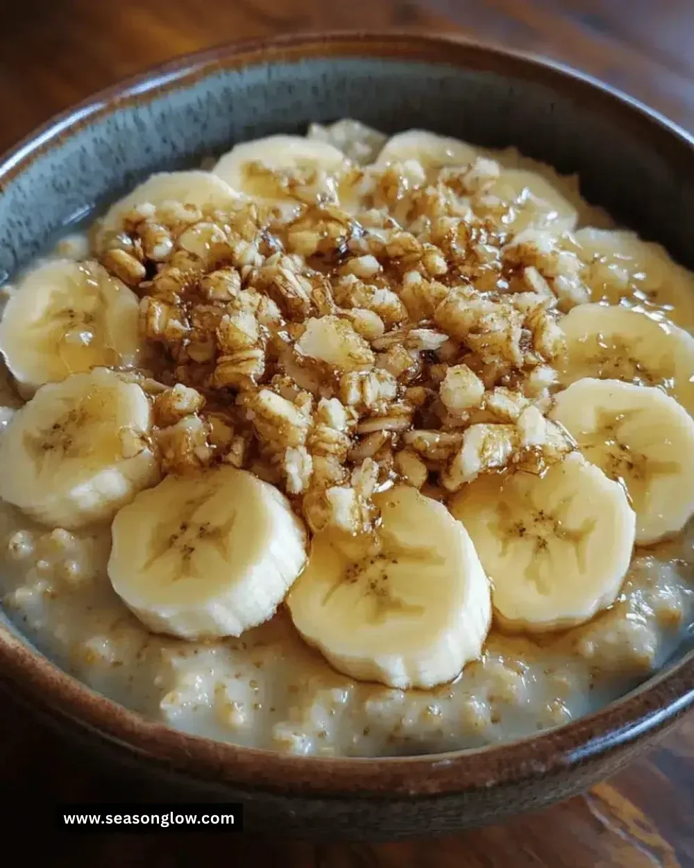 Bowl of warm maple banana porridge topped with sliced bananas and maple syrup.
