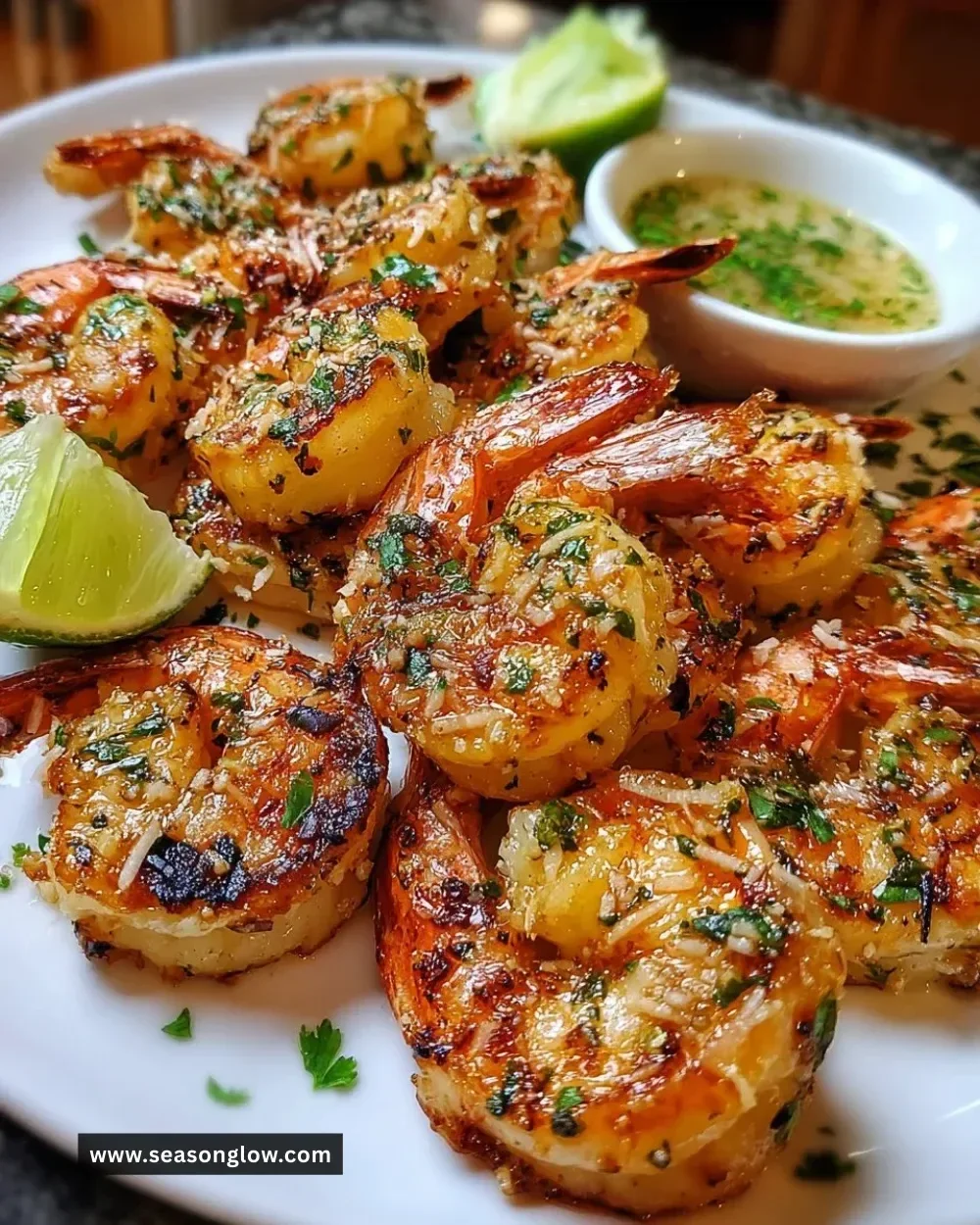 Plate of grilled coconut lime shrimp with lime wedges and fresh herbs