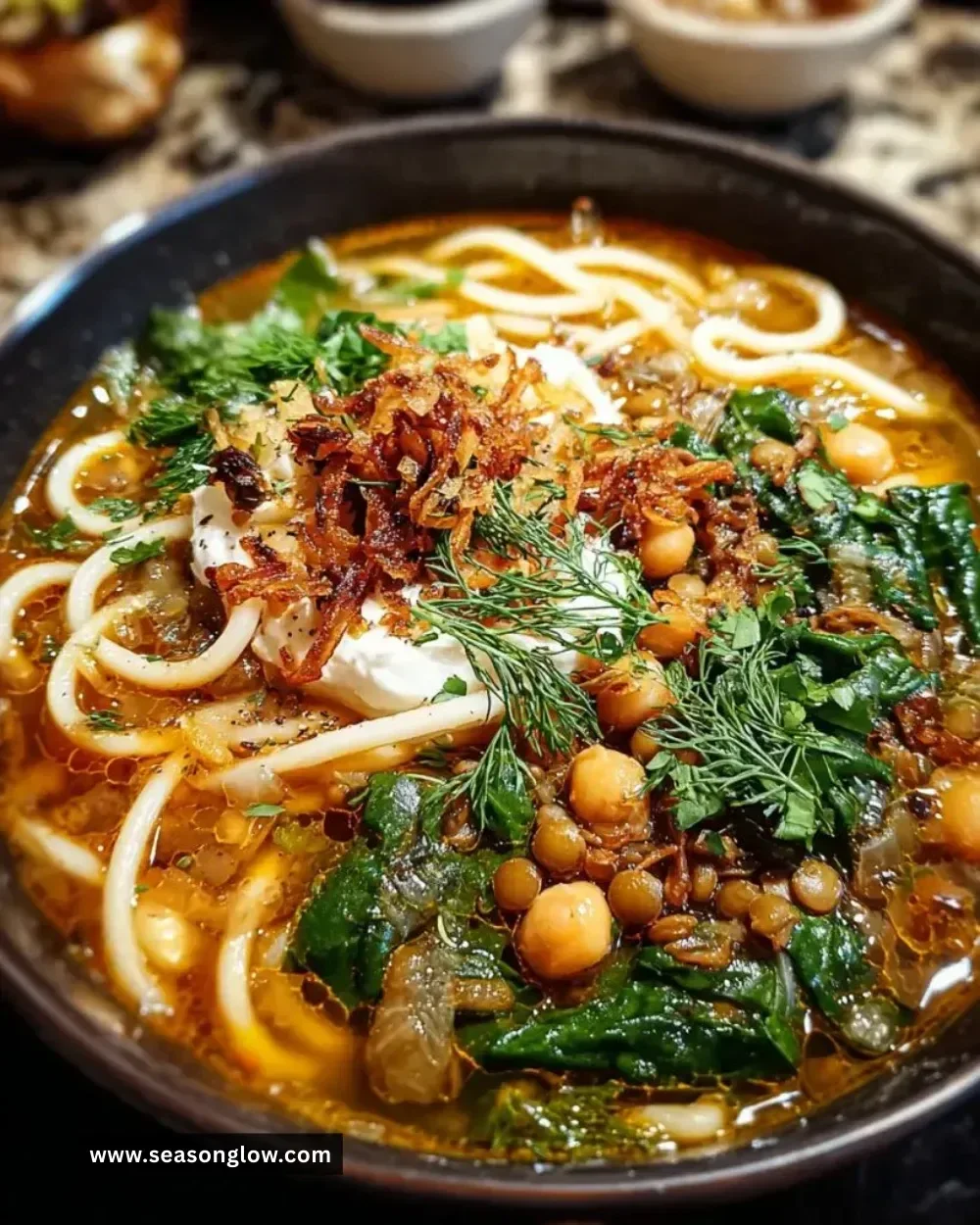 Bowl of Persian noodle soup with herbs, noodles, and spices