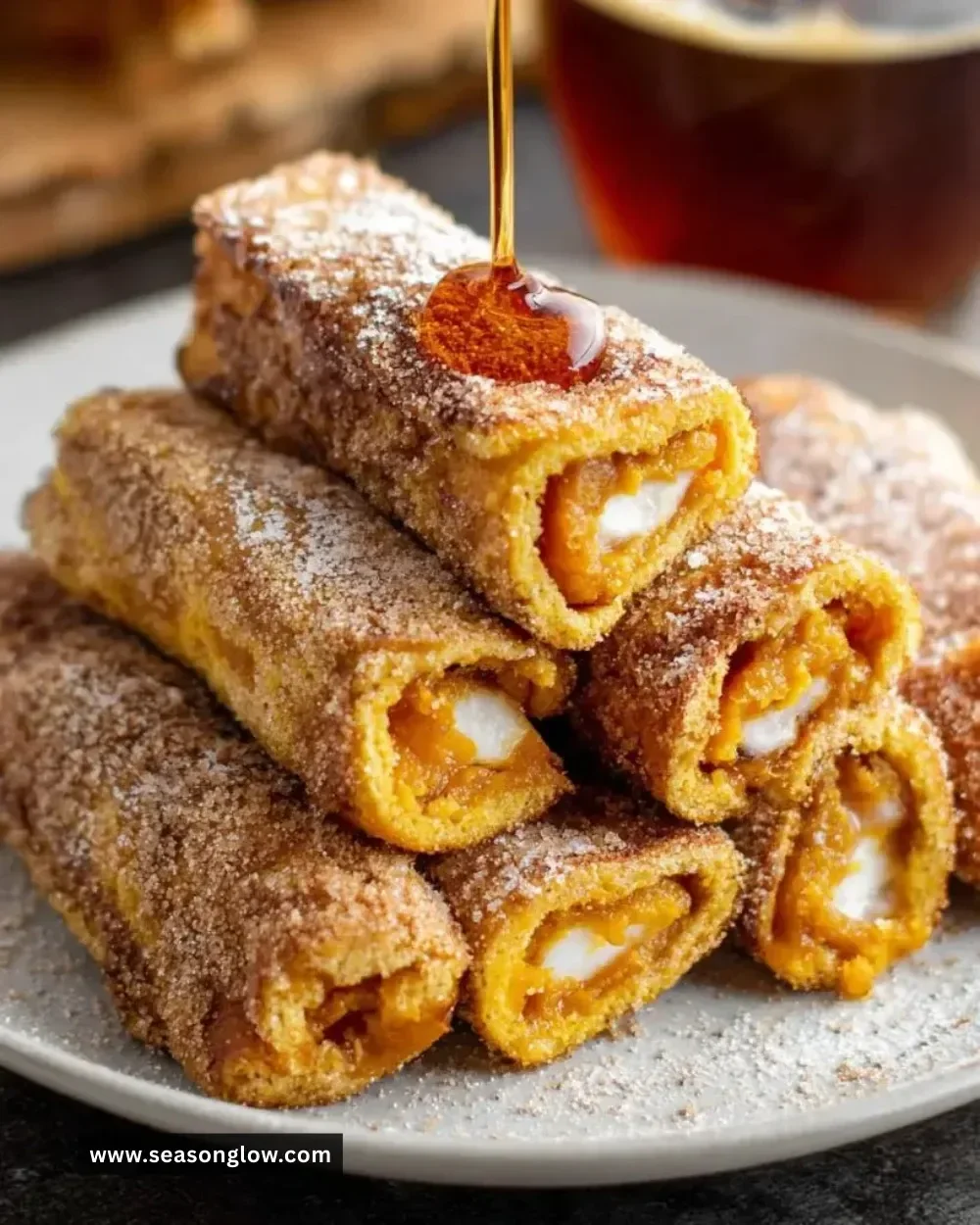 Delicious Pumpkin French Toast Roll-Ups stacked on a plate with syrup drizzle
