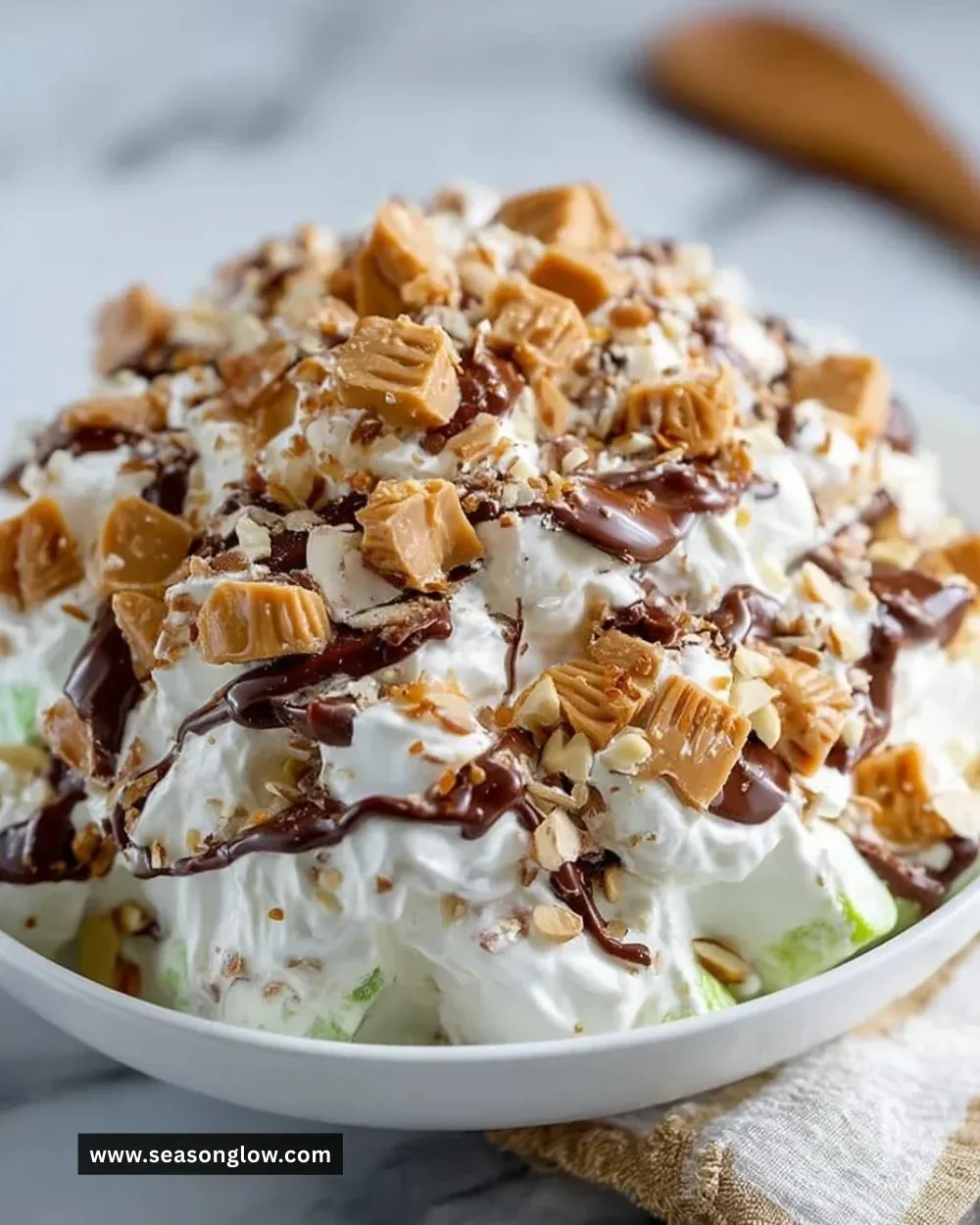 Delicious Snickers Salad with whipped topping, apples, and Snickers bars on a plate