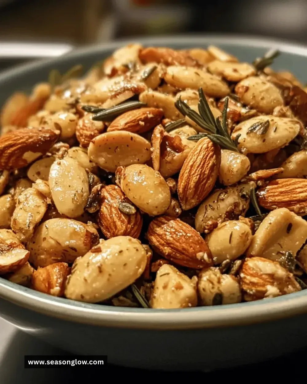 Honey Rosemary Almond Snack Mix in a bowl with fresh herbs and almonds