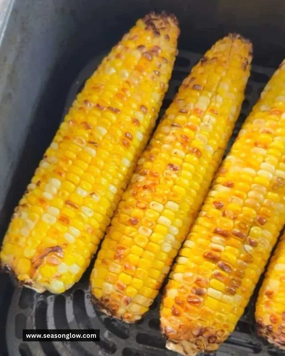 Air fryer corn on the cob served on a plate, garnished and ready to eat.