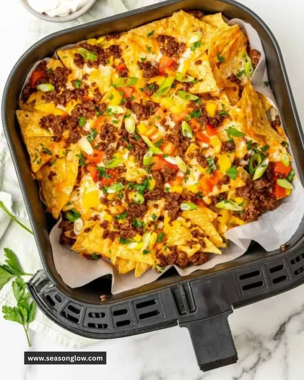 Crispy Air Fryer Nachos topped with cheese, jalapeños, and guacamole
