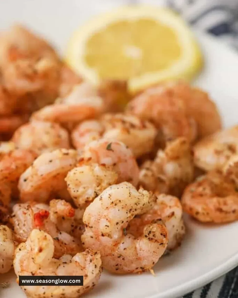 Plate of crispy air fryer shrimp garnished with lemon and herbs