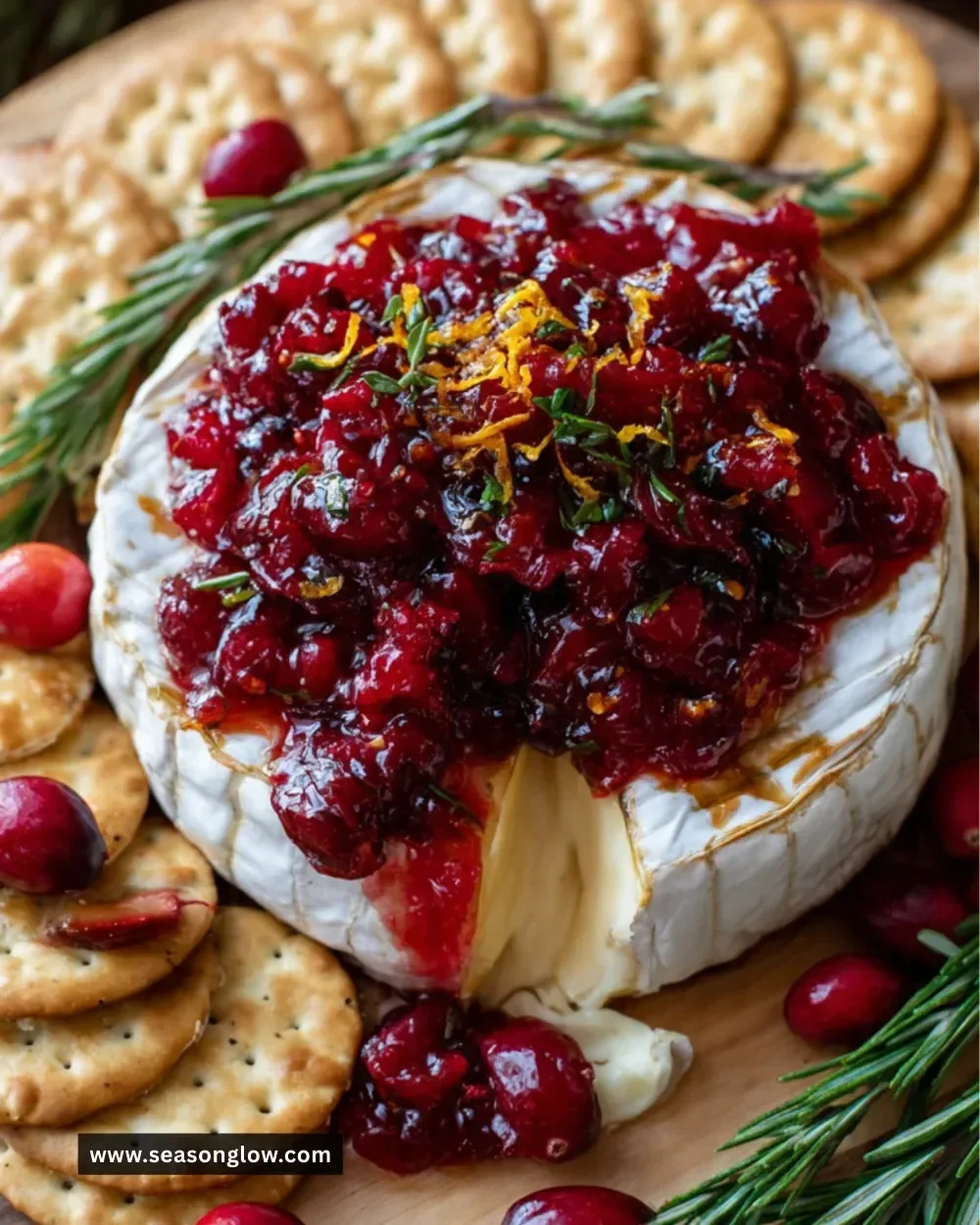 Baked brie served with cranberry sauce on a wooden platter