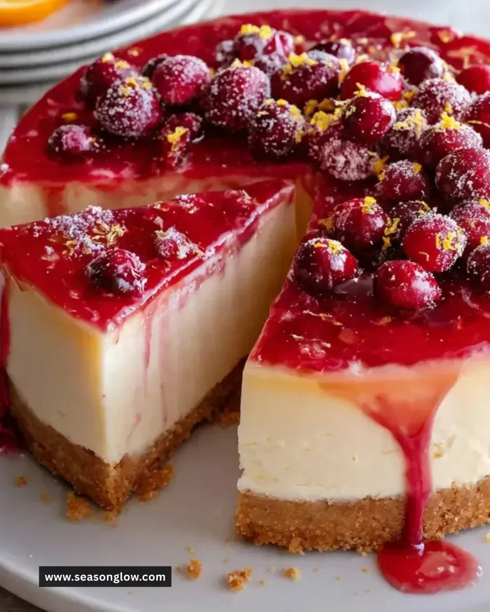 A slice of Cranberry Orange Cheesecake topped with cranberries and orange zest.