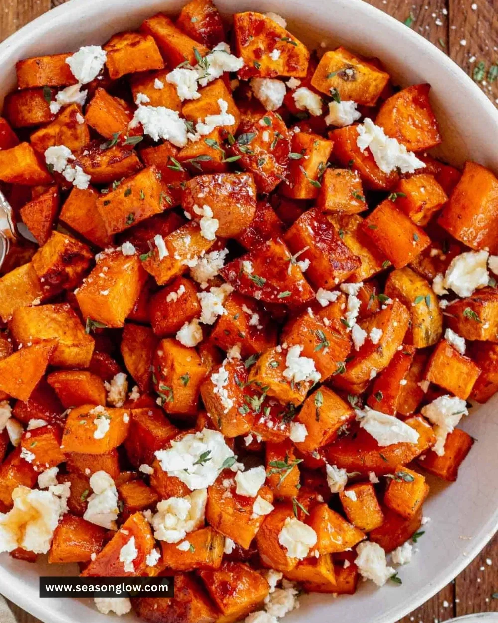 Honey roasted sweet potatoes served in a bowl garnished with herbs
