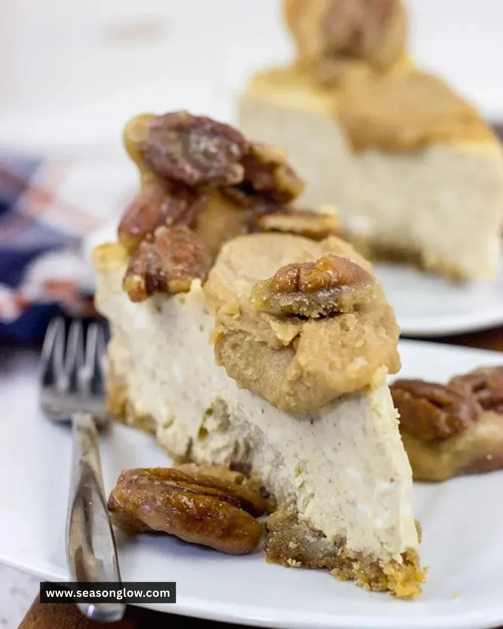 Delicious Maple Pecan Praline Cheesecake topped with pecans and drizzled in maple syrup.