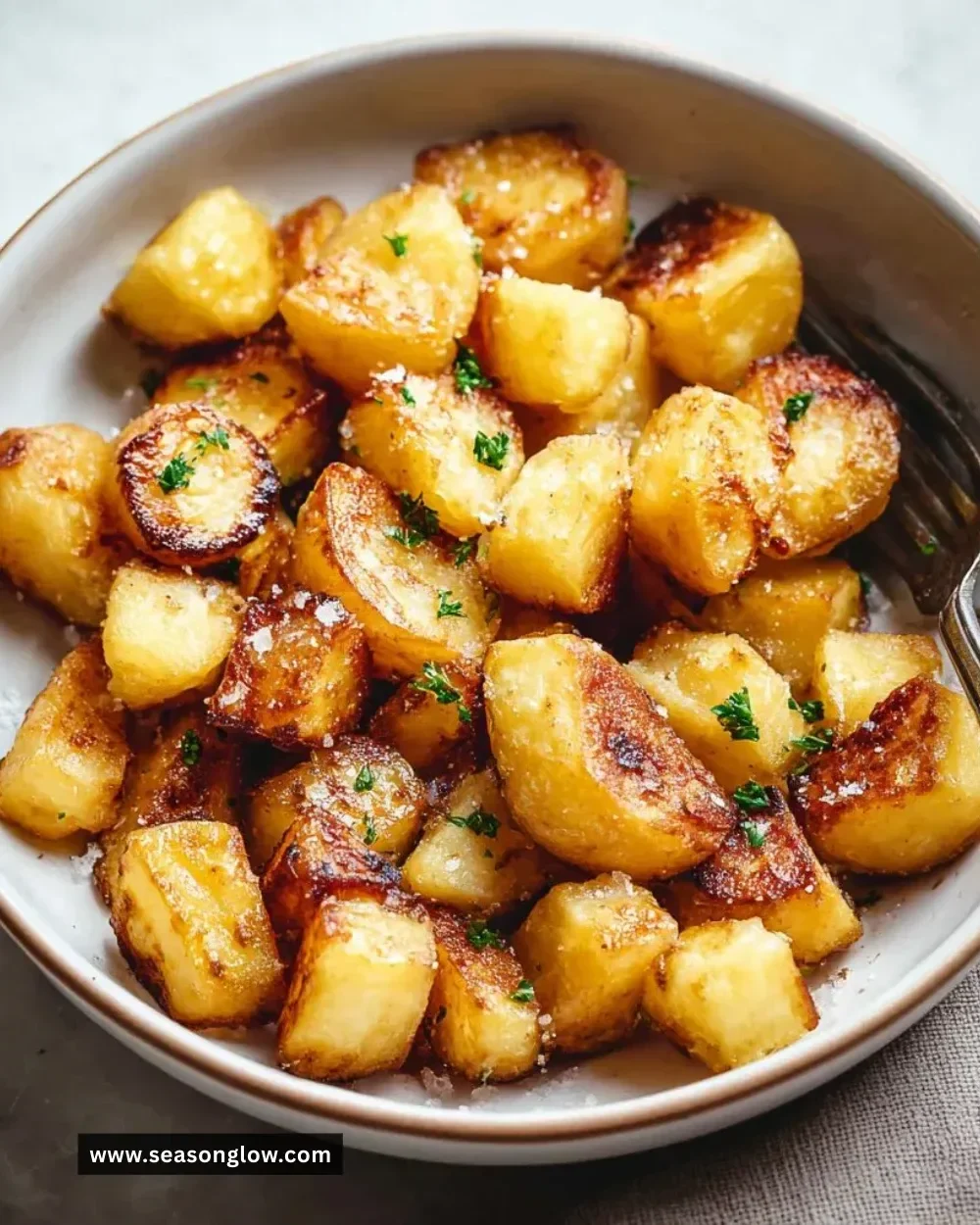 Crispy pan fried potatoes served in a bowl, garnished with herbs.